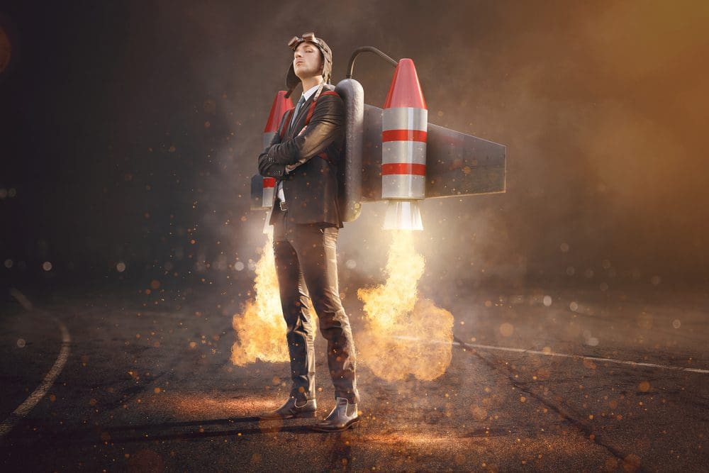 A young man in a suit with a firing rocket pack strapped on his back