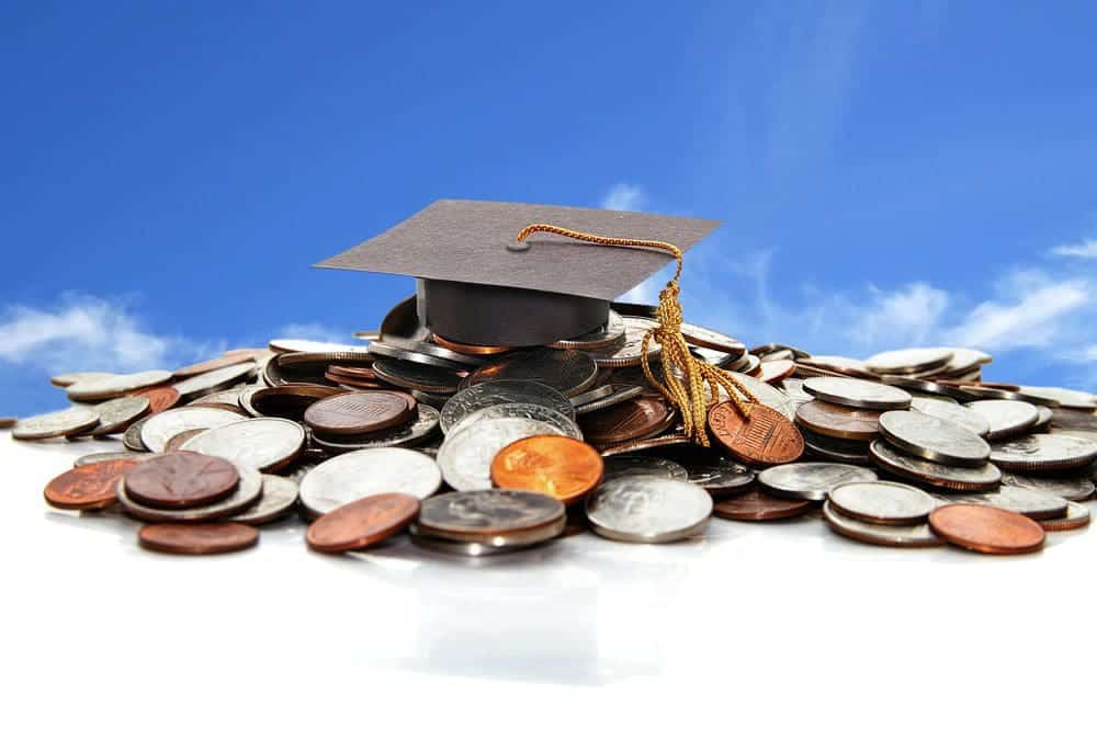 Photo of a college graduation cap resting on top of a pile of coins